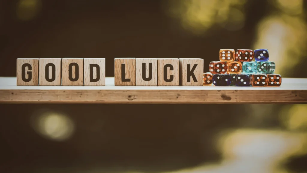 Wooden blocks spelling GOOD LUCK next to a small stack of colorful translucent dice, evaluating fairness features in a digital Dice Generator.