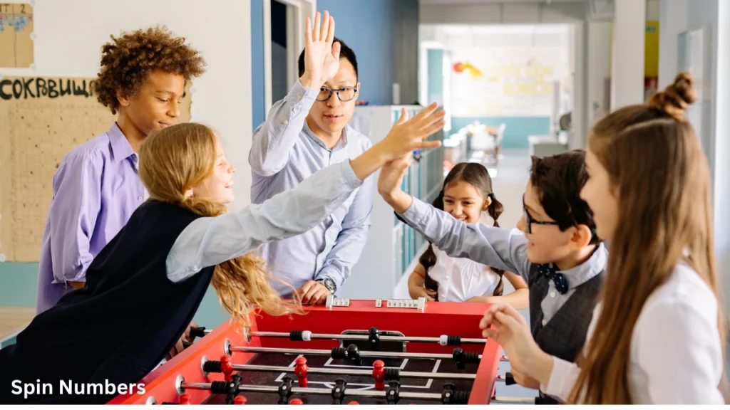 Diverse elementary school students high-fiving their teacher while enjoying interactive games in the classroom.