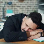 Tired businessman sleeping at desk showing how fatigue impairs the decision making process