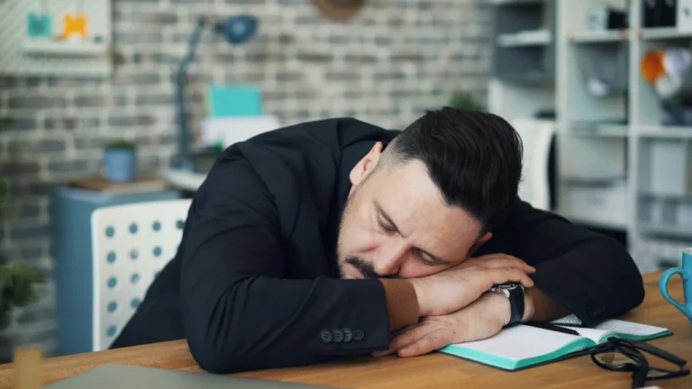 Tired businessman sleeping at desk showing how fatigue impairs the decision making process