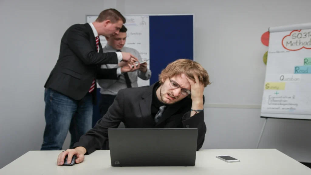 Exhausted man holding his head in front of laptop struggling with decision making process