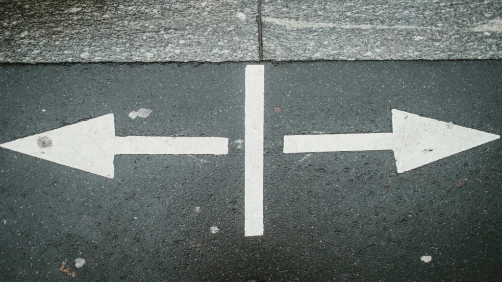 Two opposite arrows on pavement representing a difficult decision making process